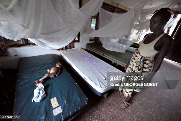 Mourir en donnant la vie, un risque tres eleve au Liberia by Isabelle LIGNER A young mother stands by her sick child sleeping on a bed at the Phebe...