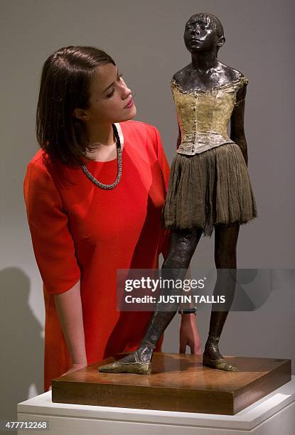 An employee of Sotheby's auction house poses by "Petite danseuse de quatorze ans" by French artist Edgar Degas, executed in wax circa 1879-81 and...