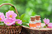 Wicker basket with rose hip flowers and bottles of oil