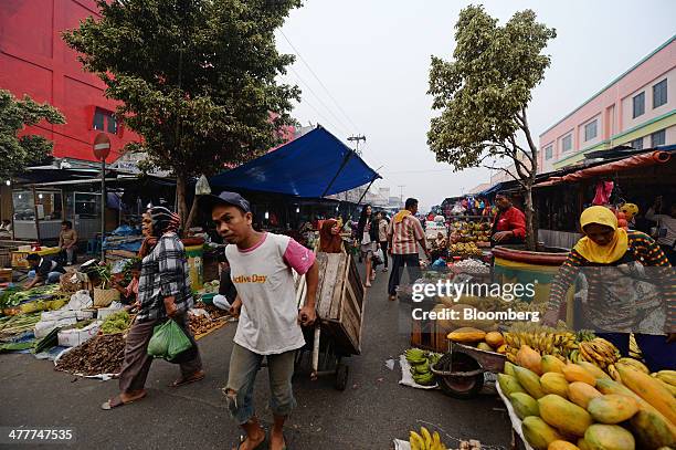 Laborer pulls a cart through a market in Pekanbaru, Riau Province, Indonesia on Friday, March 7, 2014. Indonesian central bank Governor Agus...