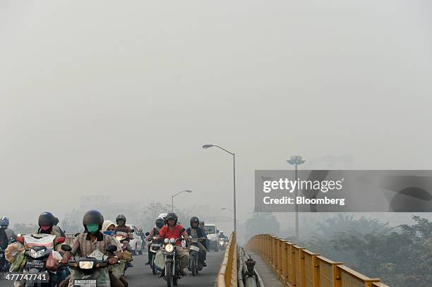 Motorcyclists cross a bridge over the Siak river shrouded in haze in Pekanbaru, Riau Province, Indonesia on Friday, March 7, 2014. Indonesian central...