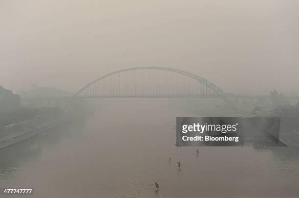 New bridge under construction over the Siak river stands shrouded in haze as kayakers paddle past in Pekanbaru, Riau Province, Indonesia on Friday,...