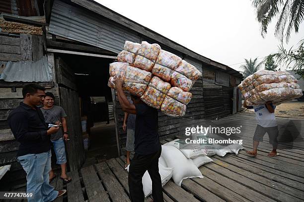 Laborers carry loads of goods into a shed near the Siak river in Pekanbaru, Riau Province, Indonesia on Friday, March 7, 2014. Indonesian central...