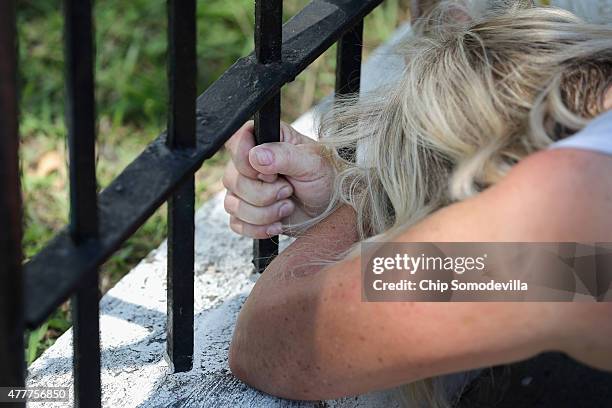 Woman clutches the fence as she prays outside the historic Emanuel African Methodist Episcopal Church where nine people were shot to death this week...