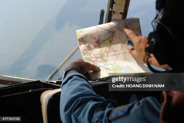 This picture taken aboard a Vietnamese Air Force Russian-made MI-171 helicopter shows a crew member checking a map during a search flight some 200 km...