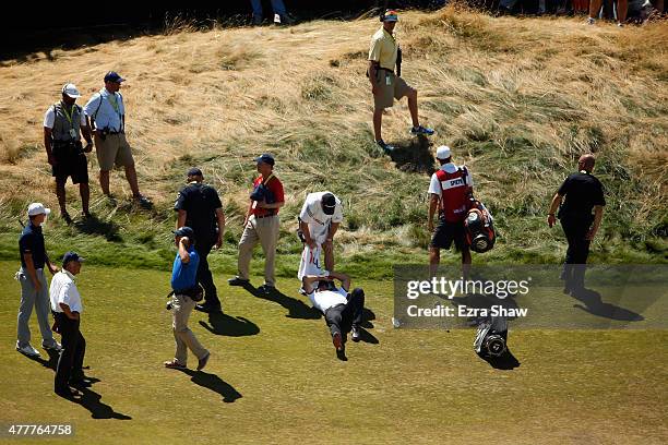 Jason Day of Australia is overcome by dizziness and lays on the ninth hole as his caddie Colin Swatton looks on during the second round of the 115th...