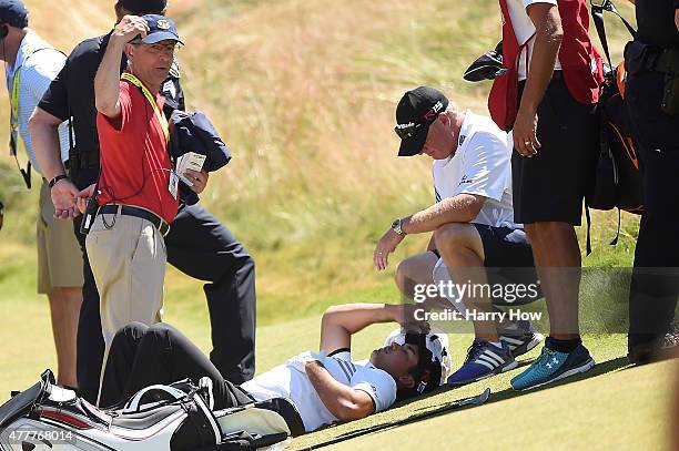 Jason Day of Australia is tended to by caddie Colin Swatton as he lays on the ninth green after falling due to dizziness during the second round of...