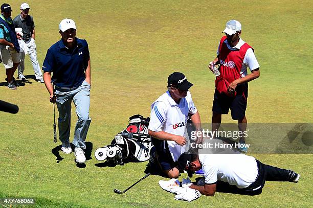 Jason Day of Australia is tended to by caddie Colin Swatton as he lays on the ninth green after falling due to dizziness during the second round of...