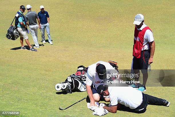 Jason Day of Australia is tended to by caddie Colin Swatton as he lays on the ninth green after falling due to dizziness during the second round of...