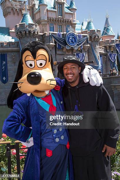 In this handout photo provided by Disney Parks, Nick Cannon poses with Goofy in his new 60th Anniversary-themed suit in front of Sleeping Beauty...