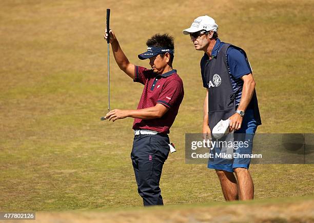 Hiroyuki Fujita of Japan and caddie Bruce Peter James line up a putt on the 16th hole during the second round of the 115th U.S. Open Championship at...