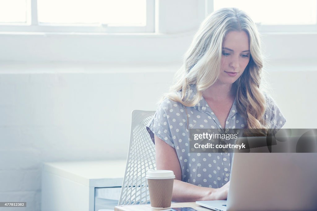 Attraktive Frau, die arbeitet auf einem laptop-computer.