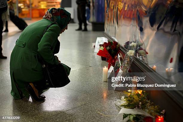 Woman looks at candles, letters and flowers placed for the victims of Madrid train bombings outside a memorial monument at Atocha railway station...