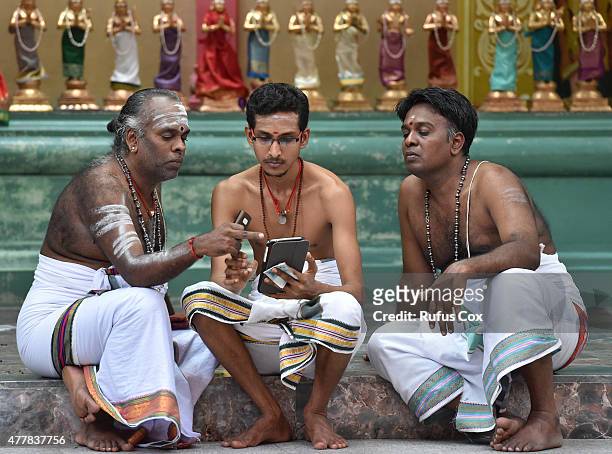Three Hindu Brahmins view a tablet device at Sri Mahamariamman Temple, the oldest Hindu temple in Kuala Lumpur, on June 19, 2015 in Kuala Lumpur,...