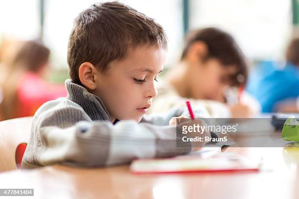 elementary student writing in a notebook during a class. - elementary school building stock pictures, royalty-free photos & images