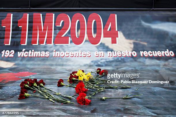 Flowers lay on a banner for the victims of Madrid train bombings during a memorial gathering outside Atocha railway station on the 10th anniversary...