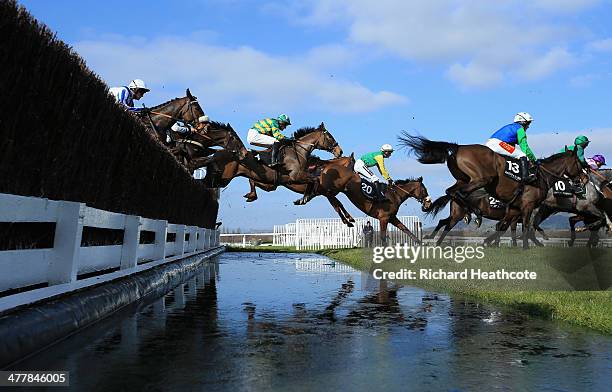 Riders in The Baylis & Harding Affordable Luxury Hanicap Steeple Chase clear the water jump during The Festival Champion Day at Cheltenham Racecourse...