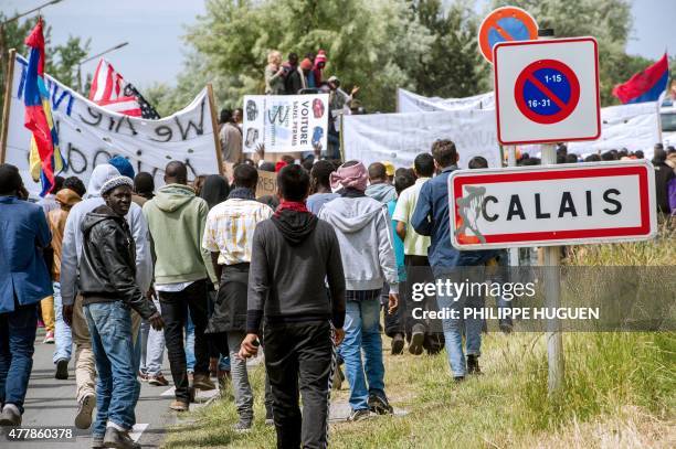 People hold banners during a demonstration of migrants in Calais, northern France, on World Refugee Day on June 20, 2015. AFP PHOTO / PHILIPPE HUGUEN