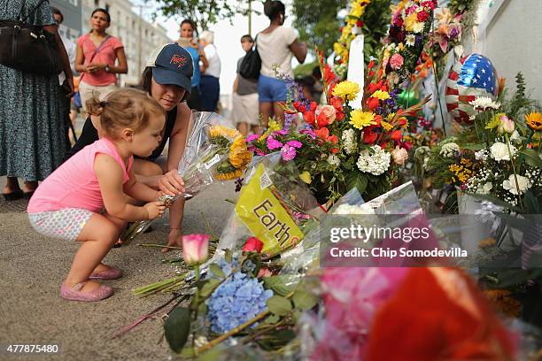 Isabelle Gudis gets a little help from her mother Charlotte Gudis while placing flowers outside the historic Emanuel African Methodist Church where...