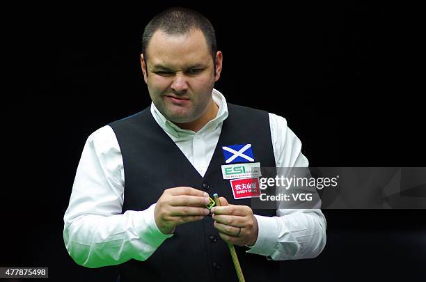Stephen Maguire of Scotland chalks his cue in quarter-finals match with John Higgins of Scotland against Ding Junhui and Xiao Guodong of China A on...