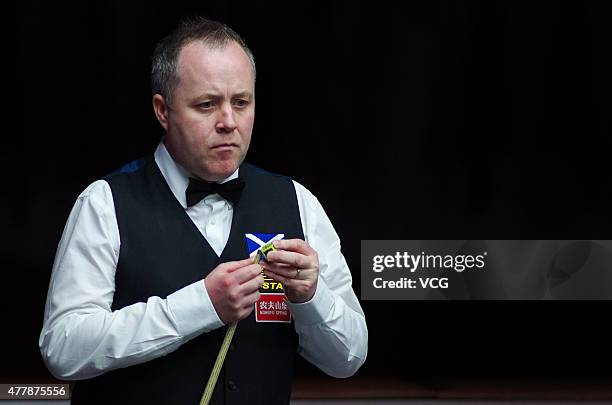 John Higgins of Scotland chalks his cue in quarter-finals match with Stephen Maguire of Scotland against Ding Junhui and Xiao Guodong of China A on...