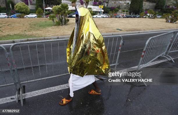 Migrant covers himself with a protection sheet as he walks under the rain near the sea, in the city of Ventimiglia at the French-Italian border, on...