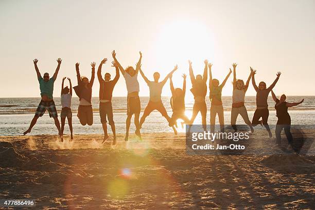 young people jumping at the beach of st.peter-ording in germany - group cheering stock pictures, royalty-free photos & images