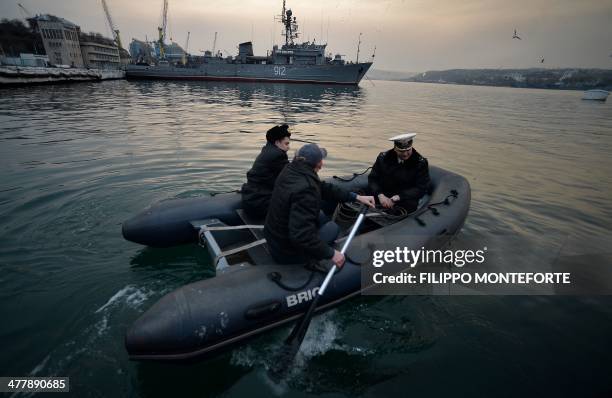 Officers from the Ukrainian navy ship Ternopil get on board of a boat in front of the Russian navy ship minesweeper "Turbinist" anchored at the...