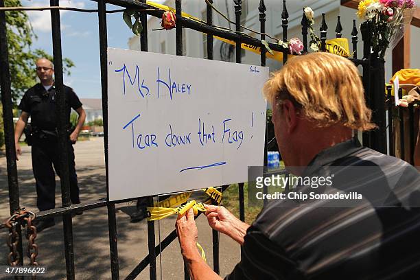 Jay Masty ties a sign that reads "Ms. Haley, Tear down that Flag!" on the fence outside the historic Emanuel African Methodist Church where nine...
