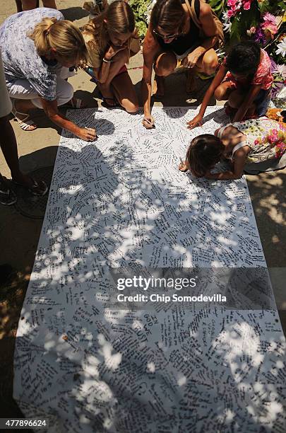 People sign their names and leave messages of hope and prayer on a poster outside the historic Emanuel African Methodist Church where nine people...