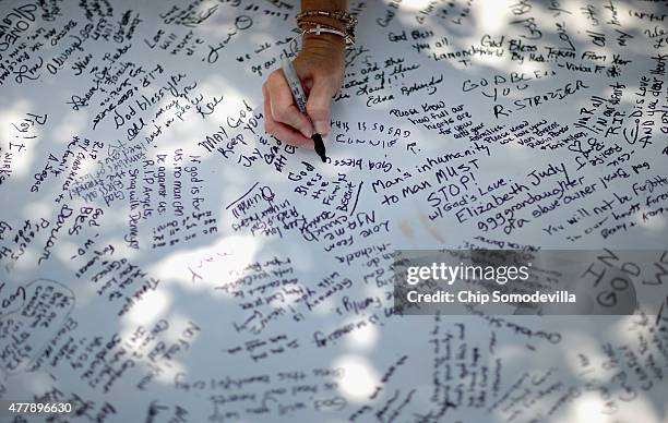 People sign their names and leave messages of hope and prayer on a poster outside the historic Emanuel African Methodist Church where nine people...