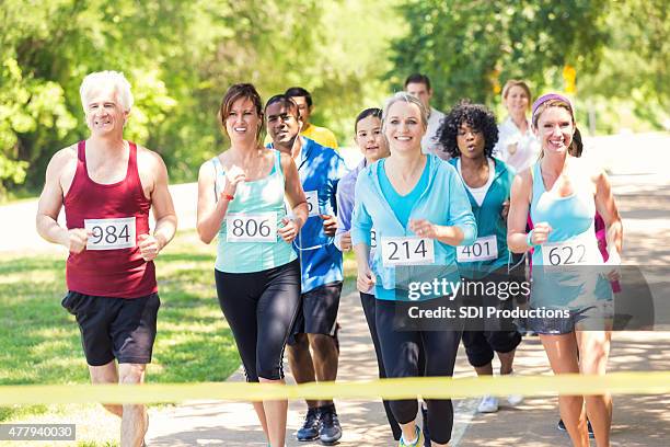 runners approaching finish line during marathon or 5k race - mixed race woman stockfoto's en -beelden