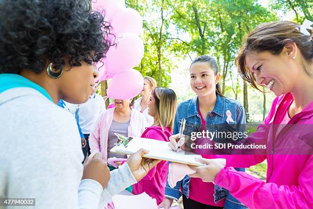 woman signing up for breast cancer awareness charity race - mixed race woman stockfoto's en -beelden