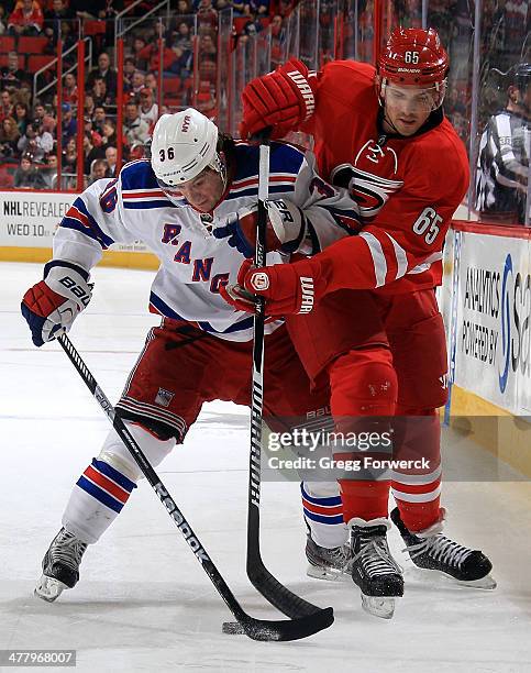 Mats Zuccarello of the New York Rangers attempts to bump Ron Hainsey of the Carolina Hurricanes off the puck during their NHL game at PNC Arena on...