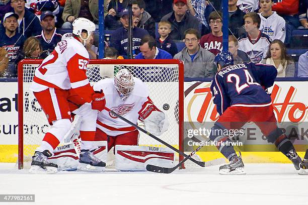 Derek Mackenzie of the Columbus Blue Jackets flips the puck past Jonathan Ericsson of the Detroit Red Wings and Petr Mrazek of the Detroit Red Wings...