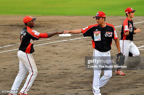 Kyuji Fujikawa of Kochi Fighting Dogs high fives with third baseman Sanfo Lassina during a practice match between Kochi Fighting Dogs and Kagawa...