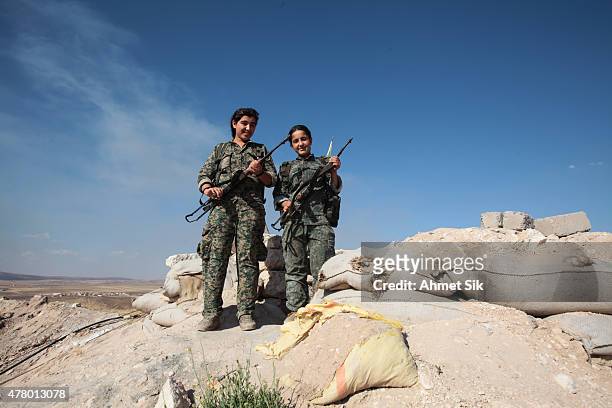 Kurdish People's Protection Units, or YPG's women fighters pose as they stand in a check point with their AK-47 at the outskirts of the destroyed...