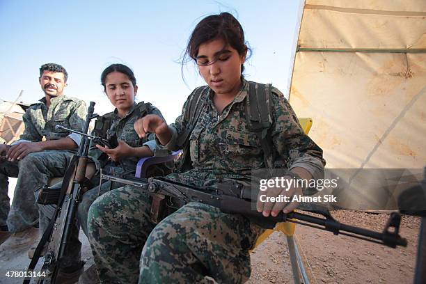 Kurdish People's Protection Units, or YPG's woman fighter controls her AK-47 in a camp at the outskirts of the destroyed Syrian town of Kobane, also...