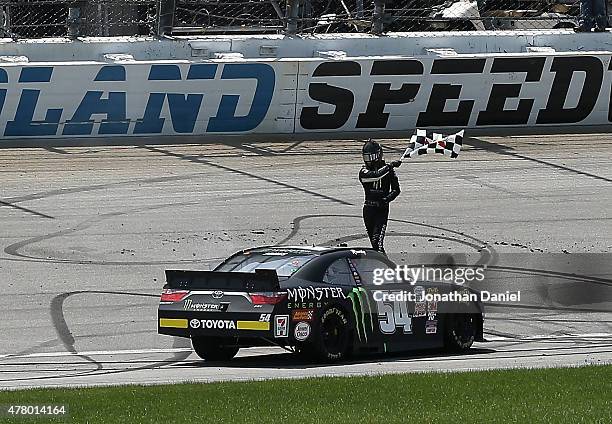 Erik Jones, driver of the Monster Energy Toyota, waves the checkered flag after winning the NASCAR XFINITY Owens Corning AttiCat 300 at Chicagoland...
