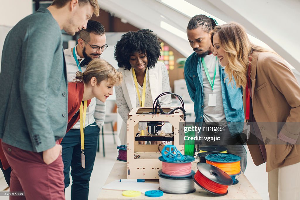 Start-Up Business Team Looking At 3D Printer.