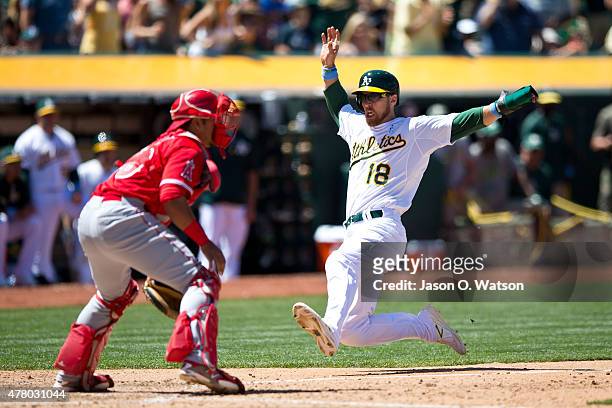 Ben Zobrist of the Oakland Athletics slides past Carlos Perez of the Los Angeles Angels of Anaheim to score a run during the sixth inning at O.co...
