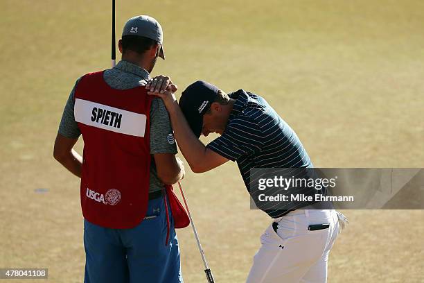 Jordan Spieth of the United States leans on his caddie Michael Greller after a birdie on the 18th green during the final round of the 115th U.S. Open...