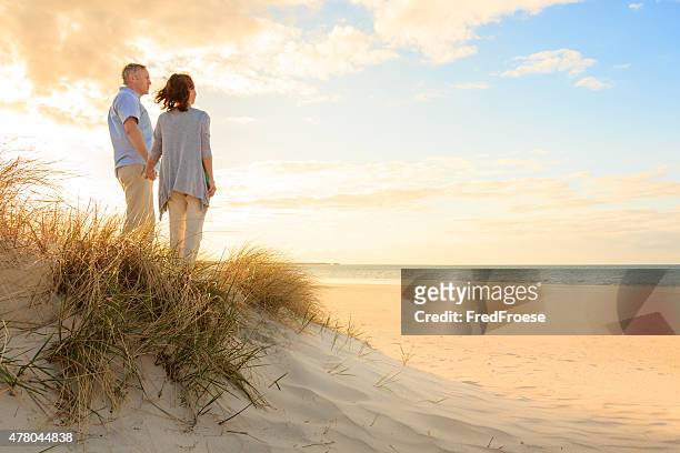 mature couple at beach - beach walking stockfoto's en -beelden