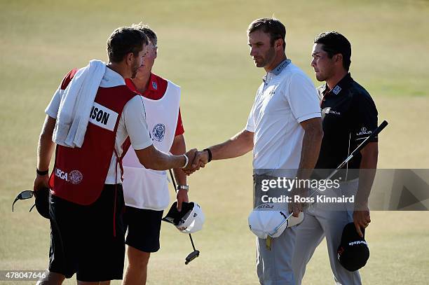 Dustin Johnson of the United States, Jason Day of Australia, caddie Colin Swatton and caddie Austin Johnson shake hands on the 18th green during the...