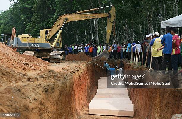 Malaysia islamic authority and villagers workers places coffins, which contain the remains of Rohingya migrants, into a grave for burial after a...