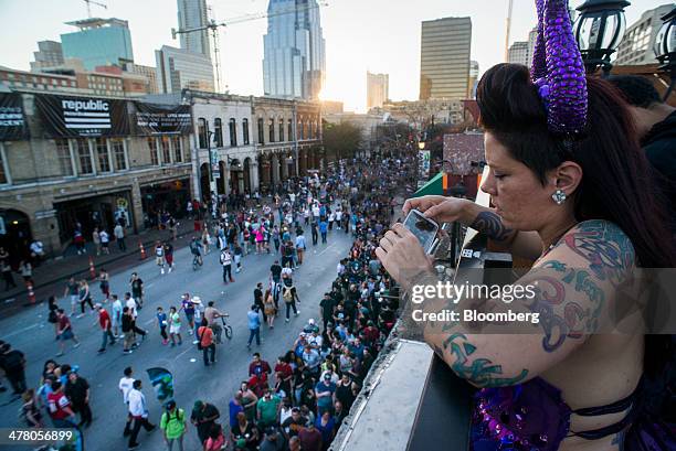 Woman uses a smartphone to take a photograph of pedestrians on 6th Street during the South By Southwest Interactive Festival in Austin, Texas, U.S.,...