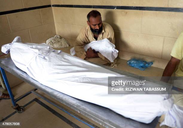 Pakistani man carries the body of his three year-old son outside the cold storage of the Edhi morgue in Karachi on June 22 after his death during a...
