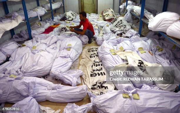 Pakistani volunteer puts a identification paper onto a body of a heatwave victim as other dead bodies are seen in the the cold storage of the Edhi...