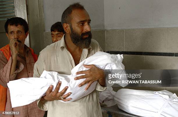 Pakistani man carries the body of his three year old son outside the cold storage of the Edhi morgue in Karachi on June 22 after his death in a...