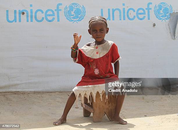 Little child sits in front of a tent in a refugee camp near the capital N'Djamena, Chad on June 21, 2015.